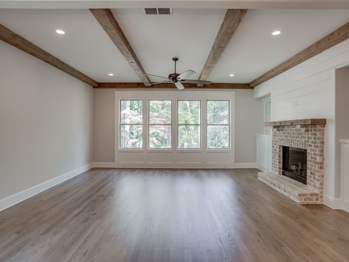 A living room floored wall to wall beside a brick fireplace, baseboard reinstalled and painted to match the trim